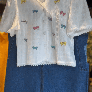 Charming White Textured Short Sleeve Button-Up Top with Multicolor Bow Embroidery and Lovely Text Print Paired with Stylish Blue Denim Midi...