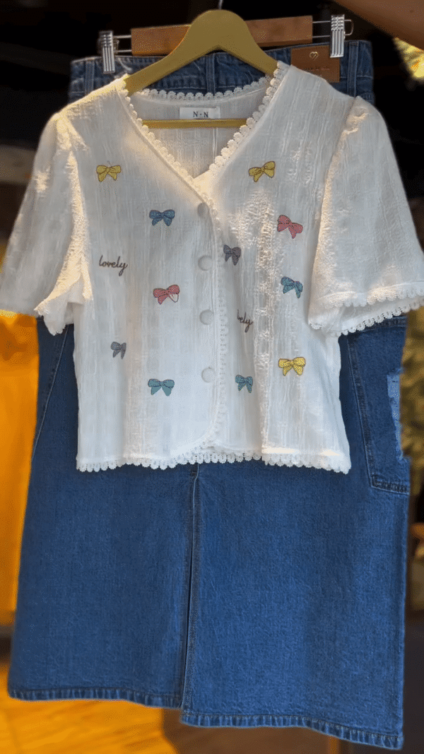 Charming White Textured Short Sleeve Button-Up Top with Multicolor Bow Embroidery and Lovely Text Print Paired with Stylish Blue Denim Midi...